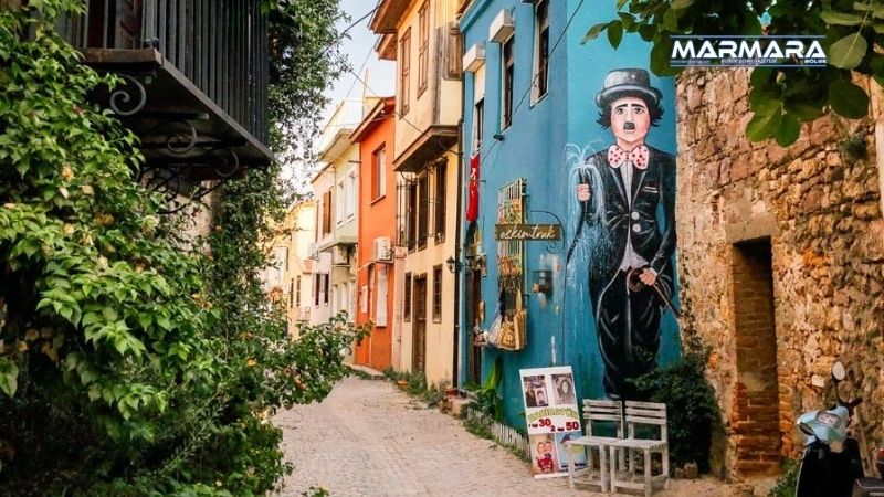 Ege’nin ruhunu taşıyan bir sokak arası düşünün… Taş duvarlar, sardunyalarla