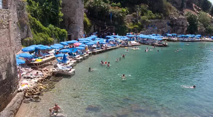 Antalya’nın tam merkezinde yer alan Mermerli Plajı, Kaleiçi’nin tarihi surlarının